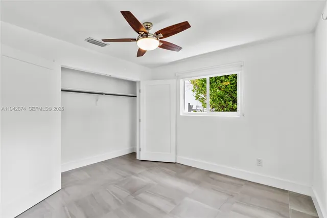 an empty room with window and ceiling fan