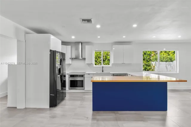 a large kitchen with stainless steel appliances granite countertop a refrigerator and a sink