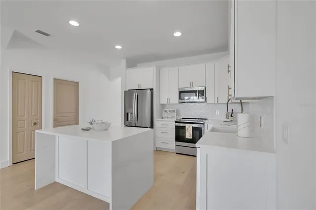a kitchen with stainless steel appliances a refrigerator stove a sink and white cabinets