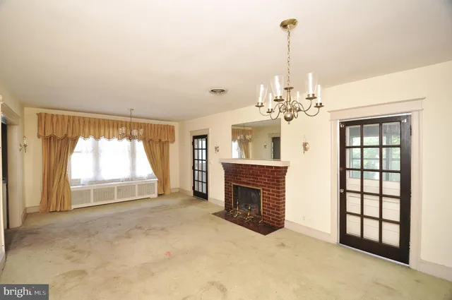 an empty room with windows and fireplace