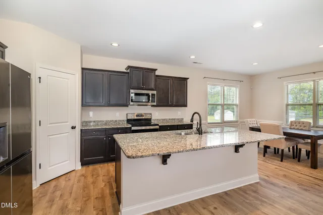 a large kitchen with stainless steel appliances granite countertop a stove a sink dishwasher a microwave oven and a refrigerator with wooden floor