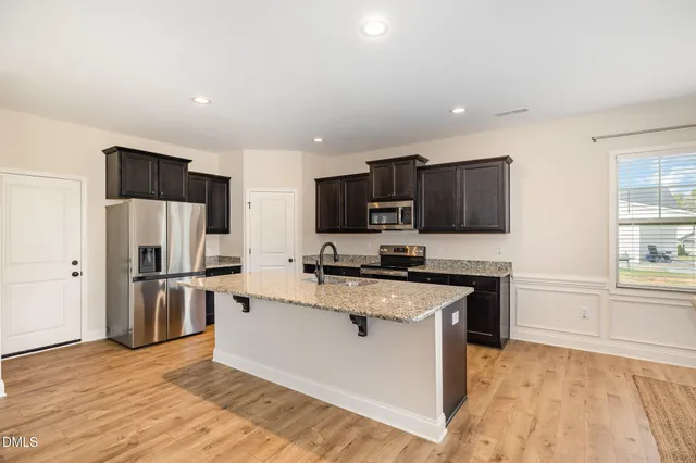 a kitchen with stainless steel appliances a stove top oven a sink a refrigerator and cabinets