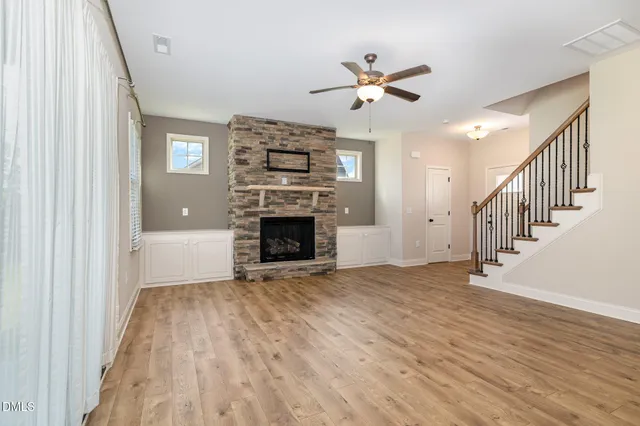 a view of an empty room with wooden floor fireplace and a window