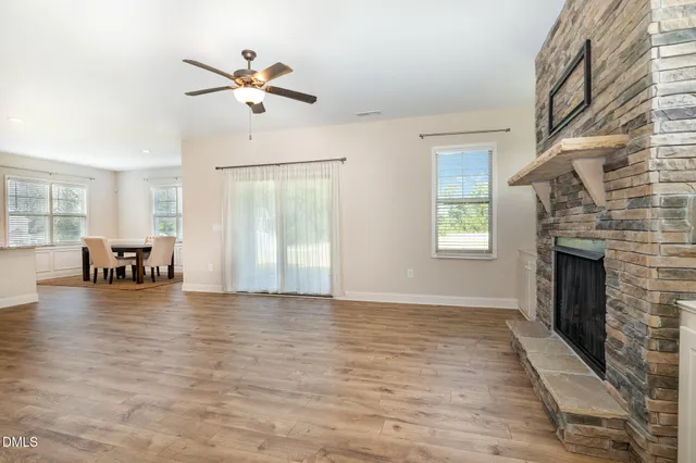 an empty room with fireplace chandelier fan and windows