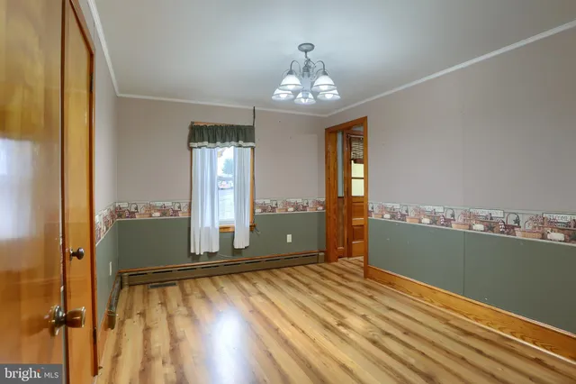 a view of a room with wooden floor chandelier and windows