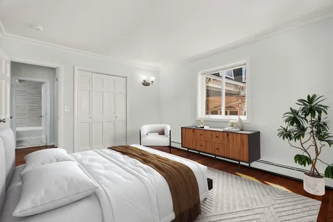 a bedroom with a bed and a potted plant next to a window