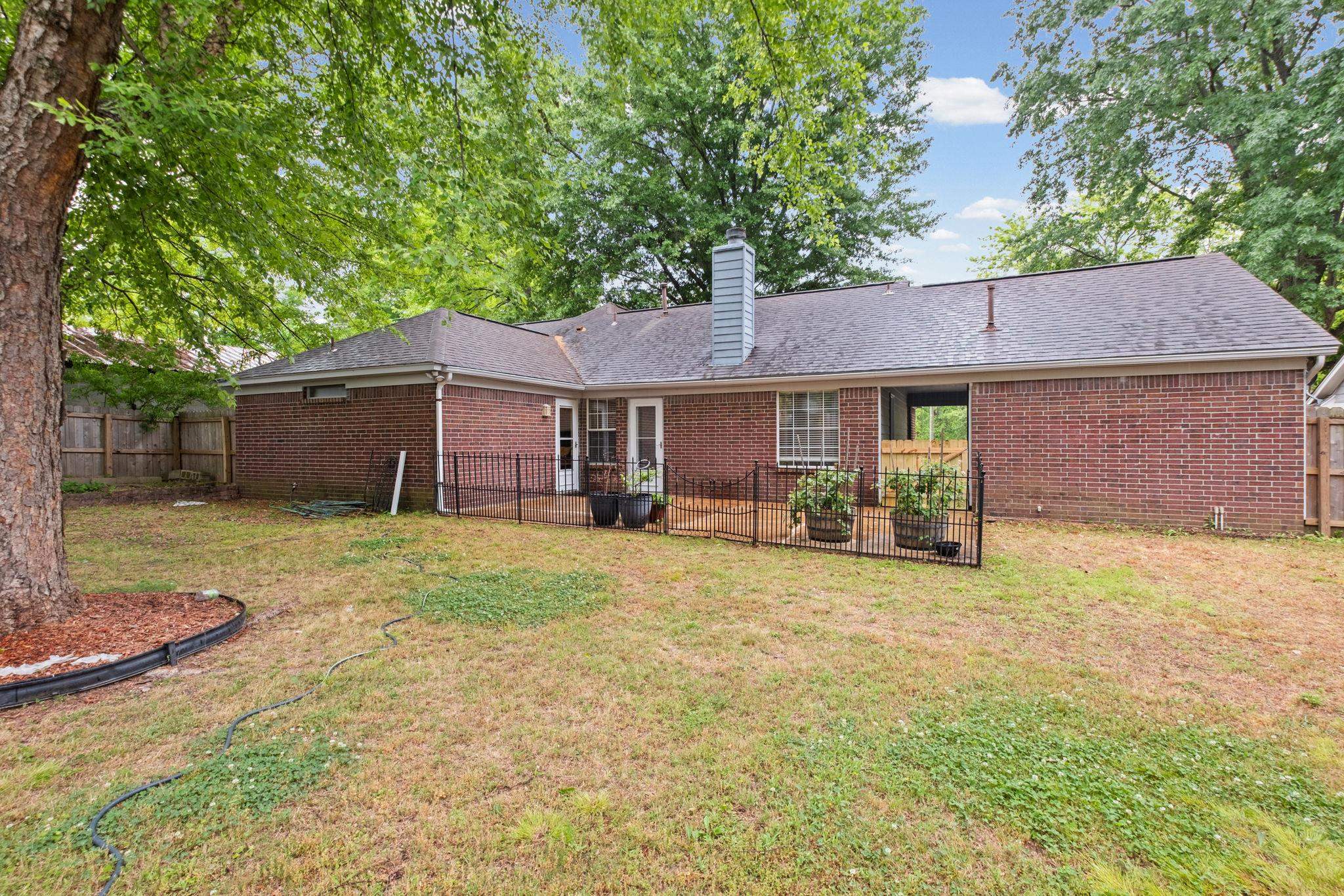 7788 Reese Road Memphis, TN 38133 - Photo 20 of 23 Patio area with a black fence, mature trees, spacious fenced yard