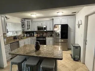 a kitchen with kitchen island granite countertop a refrigerator stove microwave and sink