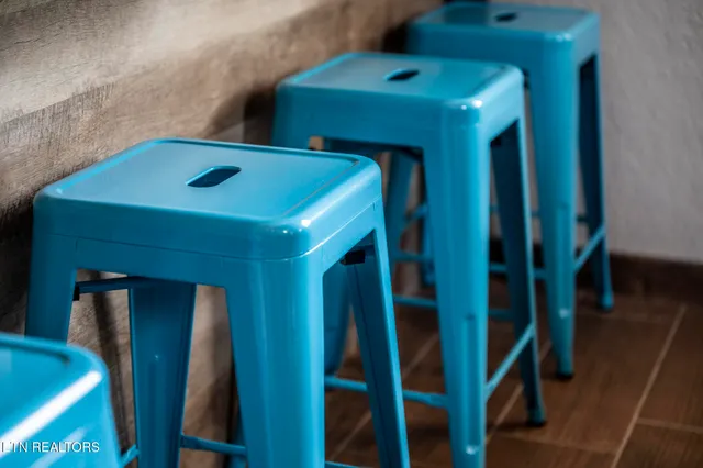 a kitchen with stainless steel appliances granite countertop a stove top oven a sink dishwasher a refrigerator and a dining table with wooden floor