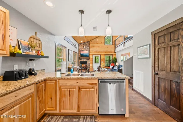 a kitchen with stainless steel appliances granite countertop a stove top oven a sink dishwasher a dining table and chairs with wooden floor