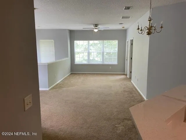 an empty room with windows and ceiling fan