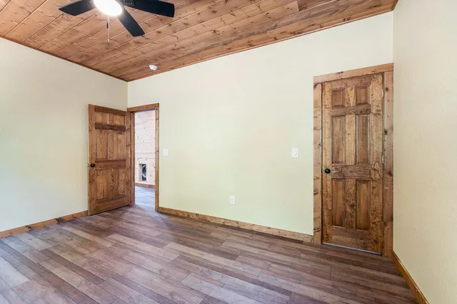 a view of an empty room with wooden floor and closet