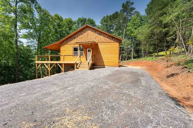 a view of backyard with wooden fence and large trees