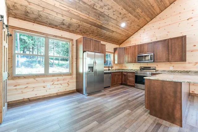 a kitchen with granite countertop wooden floors stainless steel appliances and a window