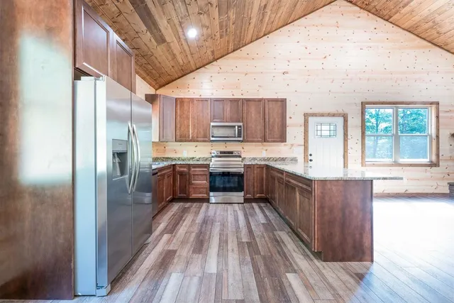 a large kitchen with a large counter top a sink stainless steel appliances and cabinets