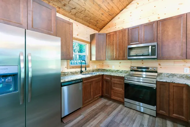 a kitchen with stainless steel appliances granite countertop wooden cabinets stove top oven and sink