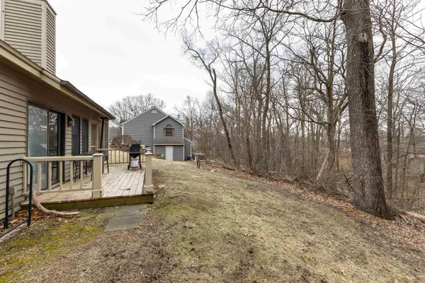 a view of house with backyard and trees in the background