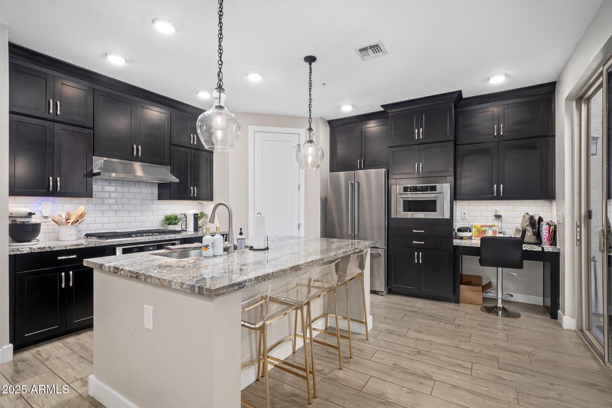 3855 South McQueen Road, Unit 21 Chandler, AZ 85286 - Photo 3 of 35 a kitchen with stainless steel appliances kitchen island granite countertop a sink a stove a refrigerator and chairs