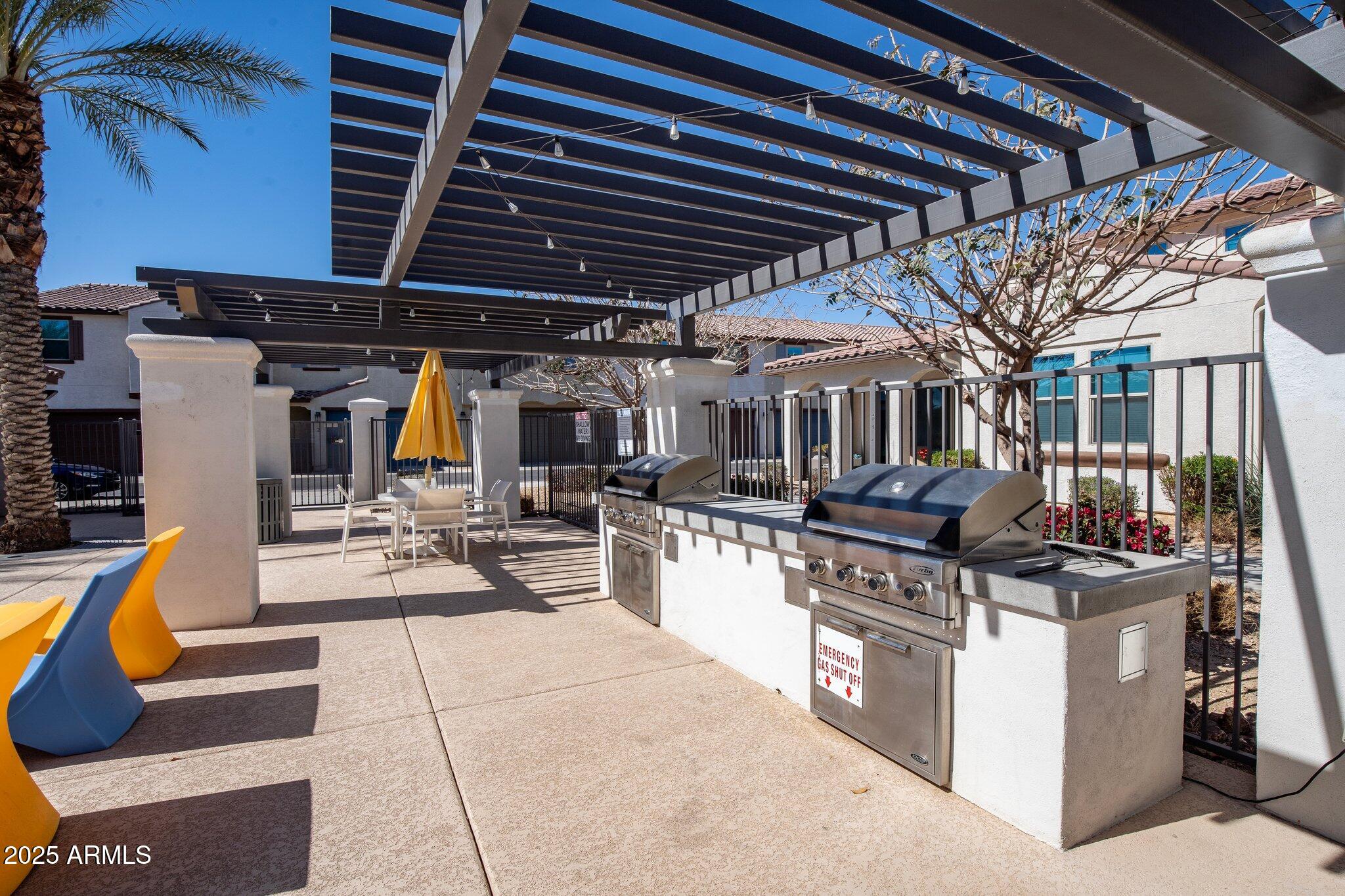 3855 South McQueen Road, Unit 21 Chandler, AZ 85286 - Photo 31 of 35 a view of a patio with dining table and chairs under an umbrella