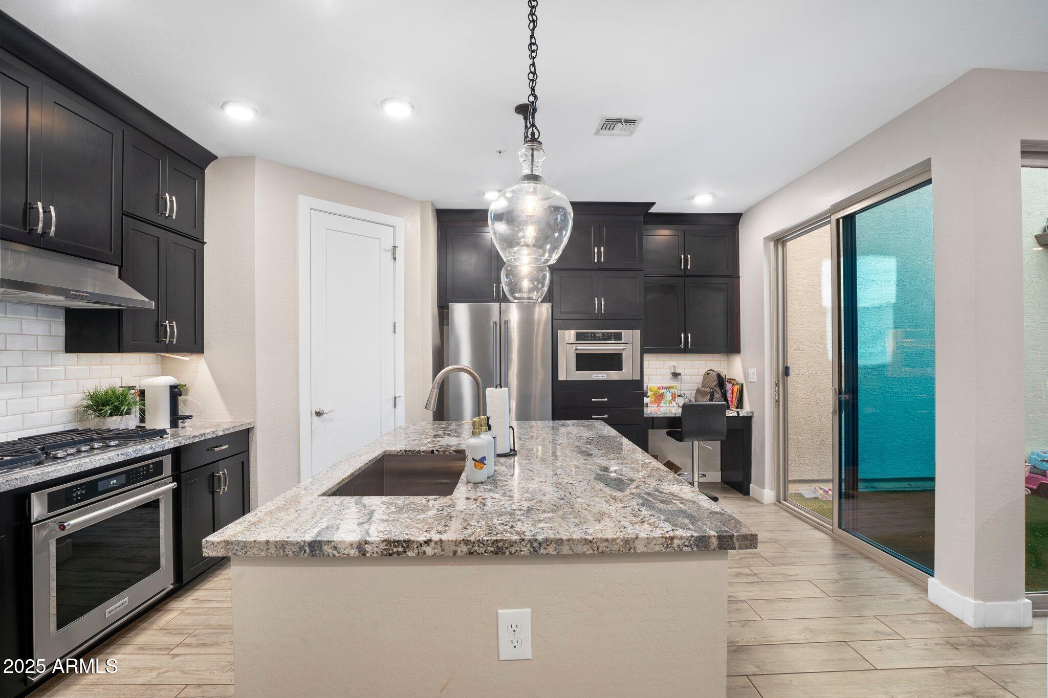 3855 South McQueen Road, Unit 21 Chandler, AZ 85286 - Photo 6 of 35 a kitchen with stainless steel appliances granite countertop a sink dishwasher a refrigerator and a dining table with wooden floor