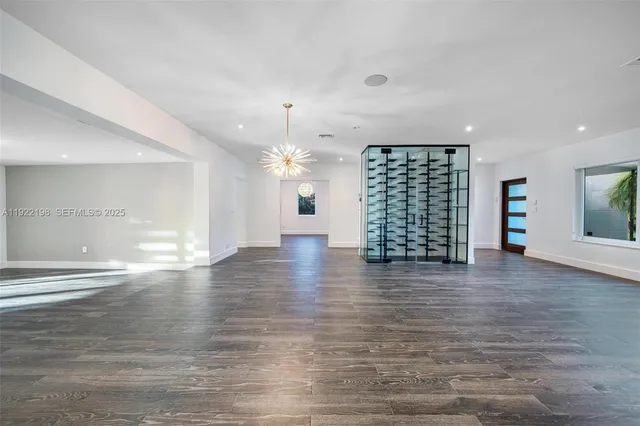 an empty room with wooden floor chandelier fan and windows