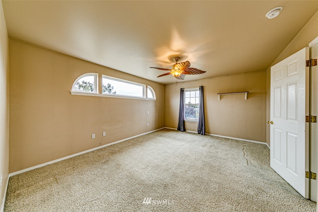 243 Griffith Farm Road Sequim, WA 98382 - Photo 22 of 35 an empty room with a chandelier fan and windows