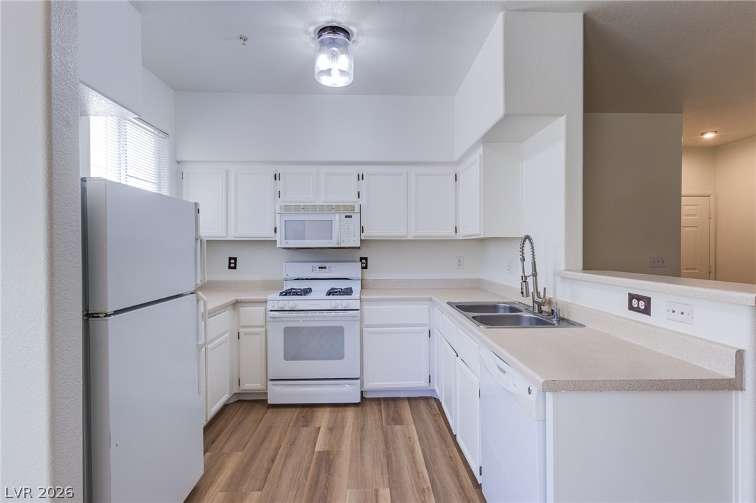 9050 West Warm Springs Road, Unit 1011 Las Vegas, NV 89148 - Photo 7 of 32 Bright, practical kitchen with wood-look flooring and ample white cabinetry.