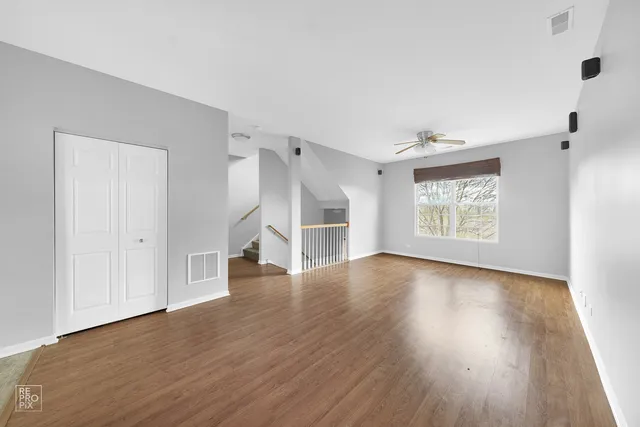 an empty room with wooden floor cabinet and windows