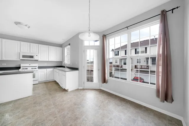 a kitchen with stainless steel appliances a refrigerator a sink a stove and white cabinets next to a window