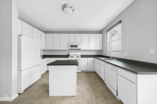 a kitchen with granite countertop white cabinets and white appliances