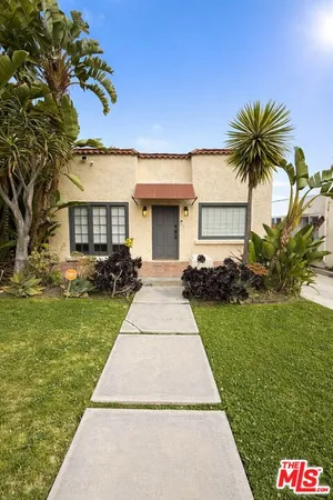 a front view of a house with a yard and potted plants