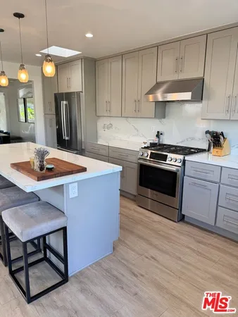 a kitchen with stainless steel appliances granite countertop a stove a sink dishwasher and a refrigerator with wooden floor