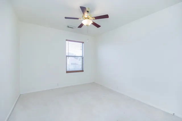 an empty room with a window and a fan