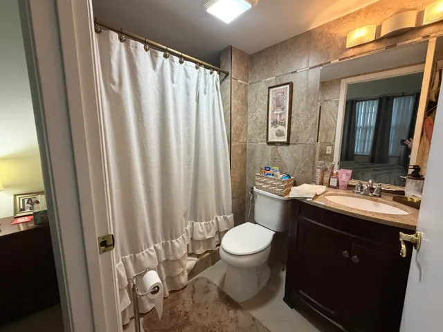 a bathroom with a granite countertop sink toilet and mirror