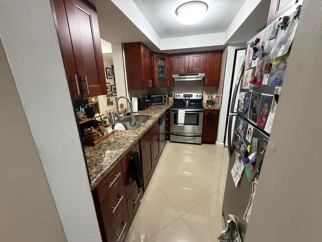 a kitchen with granite countertop a refrigerator a sink and a stove