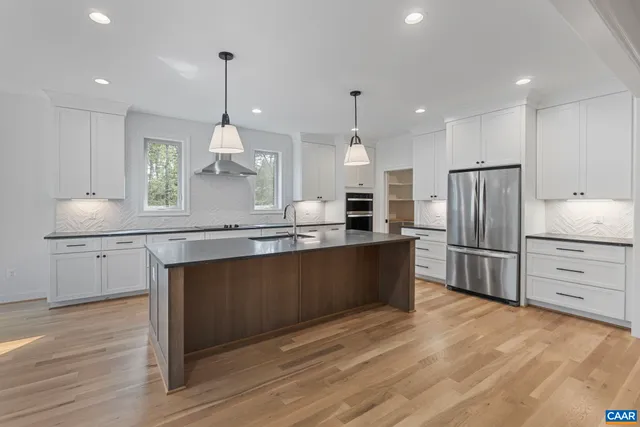 a kitchen with stainless steel appliances granite countertop a sink a stove and a wooden floors