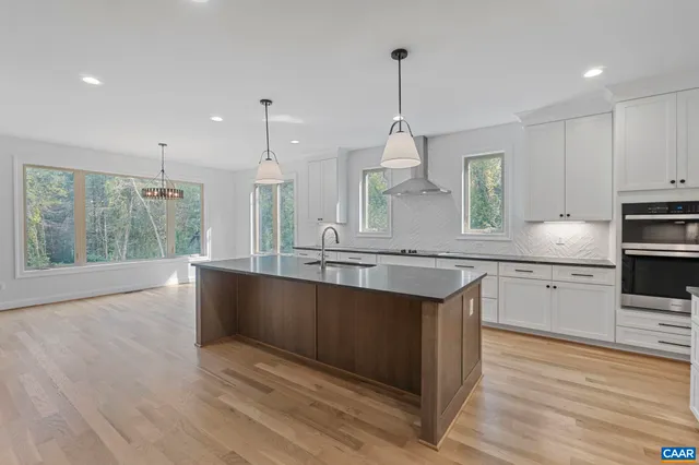 a large kitchen with stainless steel appliances granite countertop a stove and a wooden floors