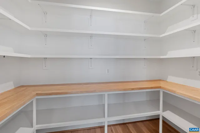 a view of an empty room with wooden floor fridge and a window