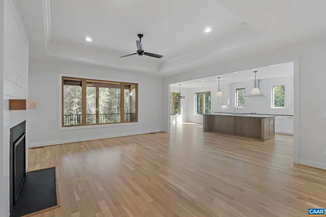 an empty room with wooden floor fireplace and windows