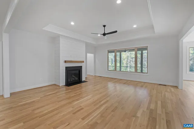 an empty room with wooden floor fireplace and windows