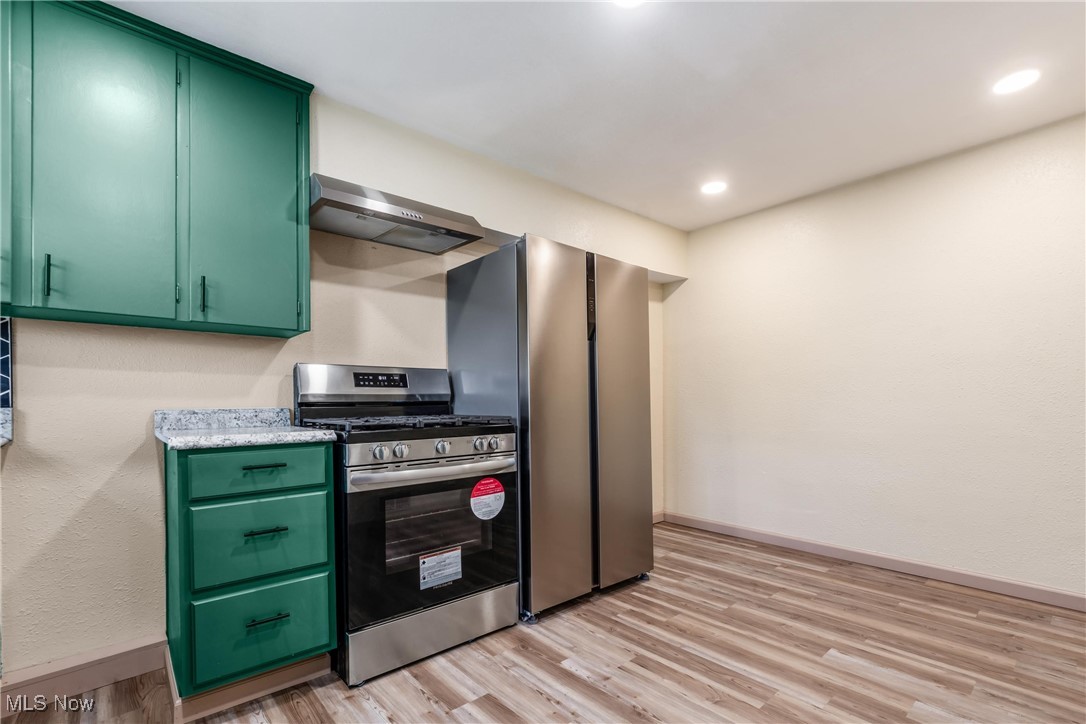 724 Garden Road Zanesville, OH 43701 - Photo 8 of 22 Kitchen with green cabinets, stainless steel appliances, light wood-style floors, wall chimney exhaust hood, and recessed lighting