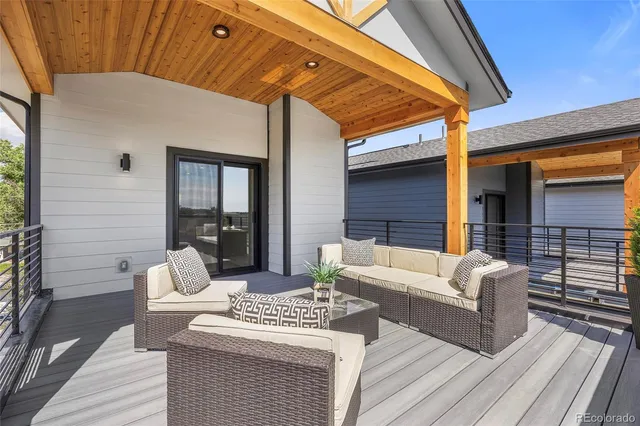 a view of a patio with couches table and chairs with wooden floor and fence