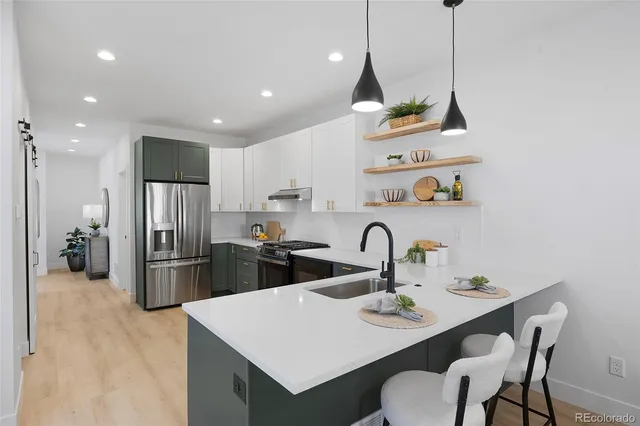 a kitchen with a refrigerator a sink a stove and chairs