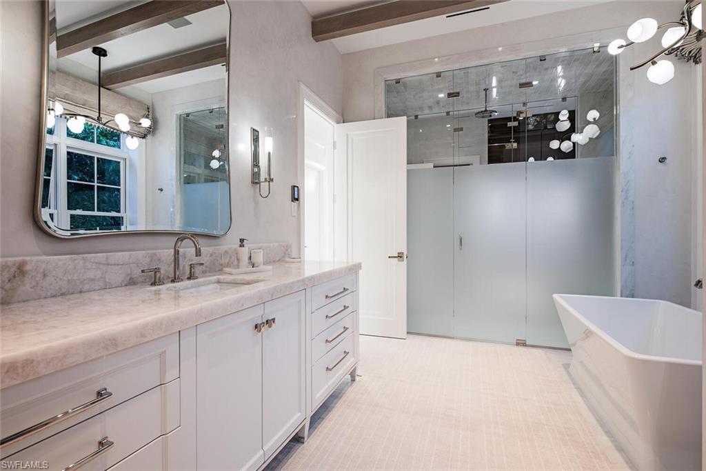 4115 Cutlass Lane Naples, FL 34102 - Photo 13 of 44 a bathroom with a granite countertop sink a large mirror and a bathtub