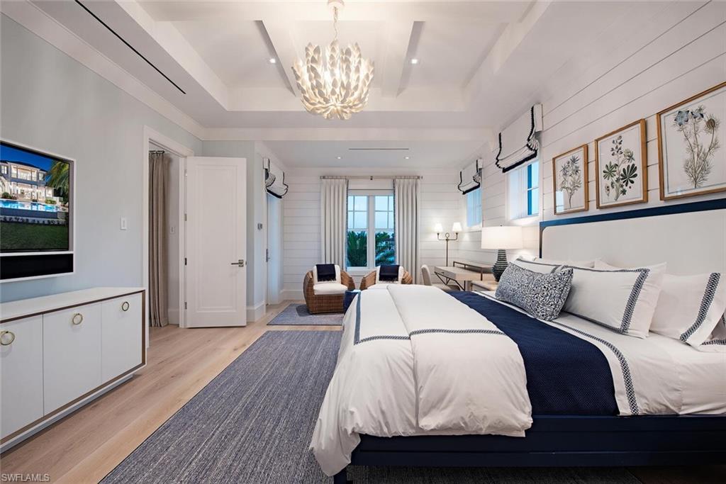 4115 Cutlass Lane Naples, FL 34102 - Photo 23 of 44 a bedroom with a large bed and a chandelier