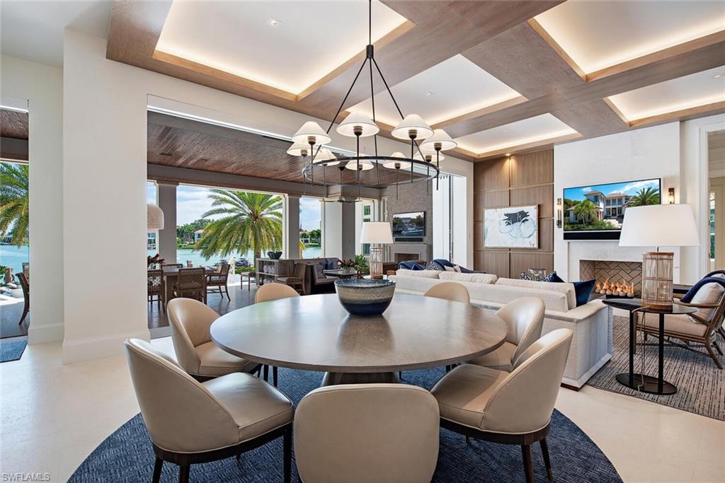 4115 Cutlass Lane Naples, FL 34102 - Photo 8 of 44 a dining room with wooden floor a chandelier a wooden table and chairs