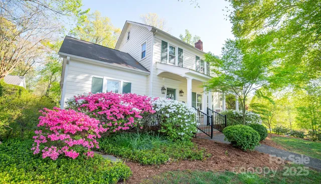 a front view of white house with a yard and fountain in middle