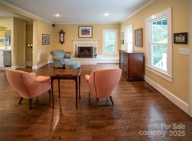 a living room with furniture a large window and wooden floor