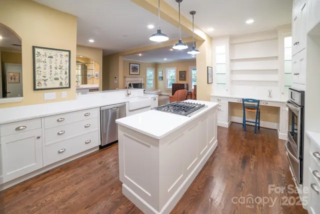 a open kitchen with kitchen island a stove a wooden floor and white cabinets