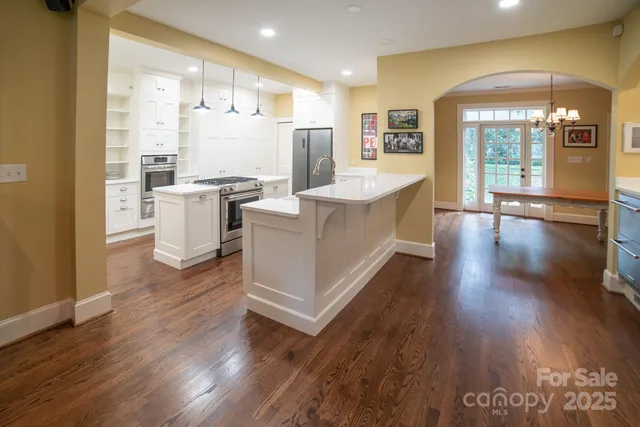 a open kitchen with white cabinets and wooden floor